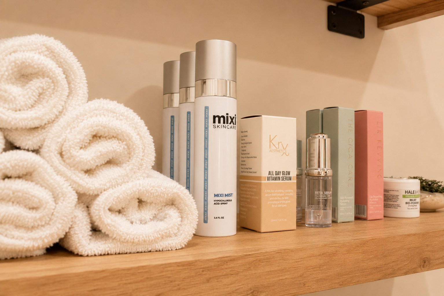 Professional skincare products and rolled towels arranged on a wooden shelf
